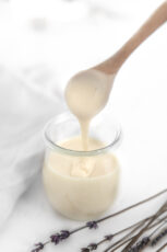 Side photo of a glass and a spoonful of vegan condensed milk