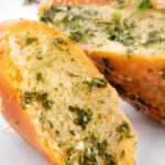 Close-up photos of some slices of vegan garlic bread with some letters