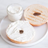 Square photo of some vegan cream cheese spread onto a bagel