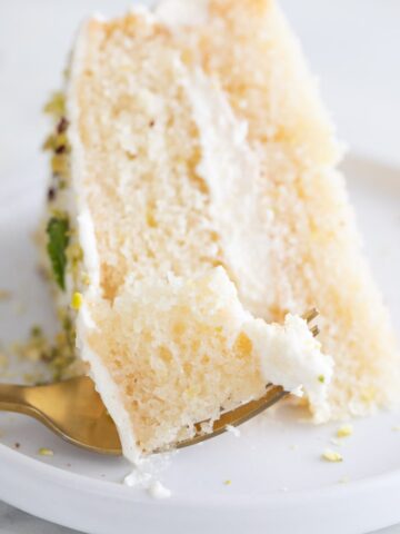 Close-up photo of a dish with a slice of vegan lemon cake and a fork