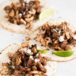 Photo of 3 jackfruit carnitas served with tortillas, lime wedges, diced onion and chopped cilantro with a heading