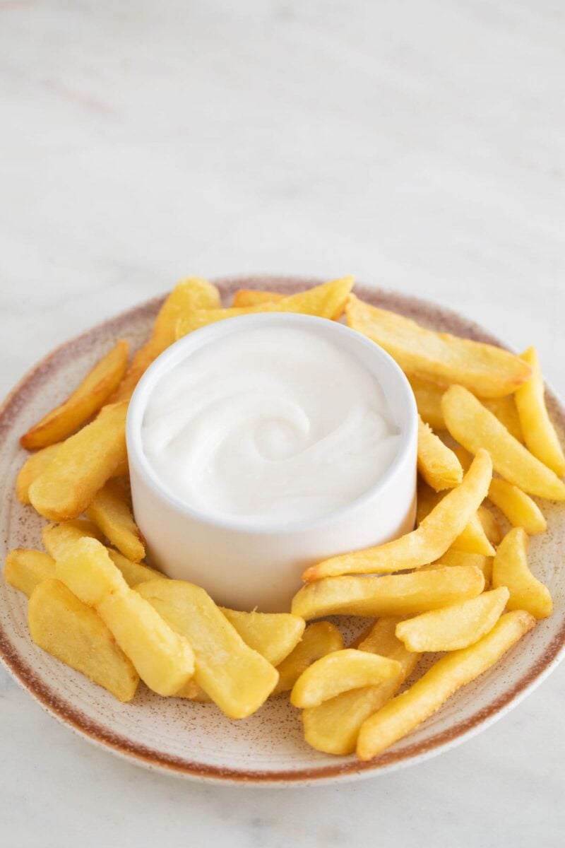 Photo of a dish with French fries and a small bowl with vegan aioli.