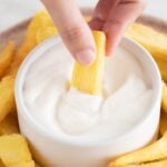 Image of a dish with french fries and a small bowl with vegan aioli and a hand dipping a fry in sauce with a title.