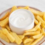 Photo of a dish with French fries and a small bowl with vegan aioli with a heading.