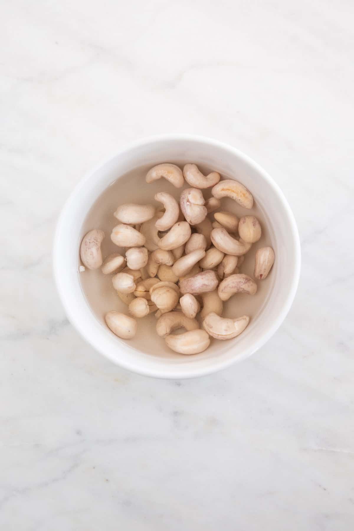 A bowl of cashews soaking in water.