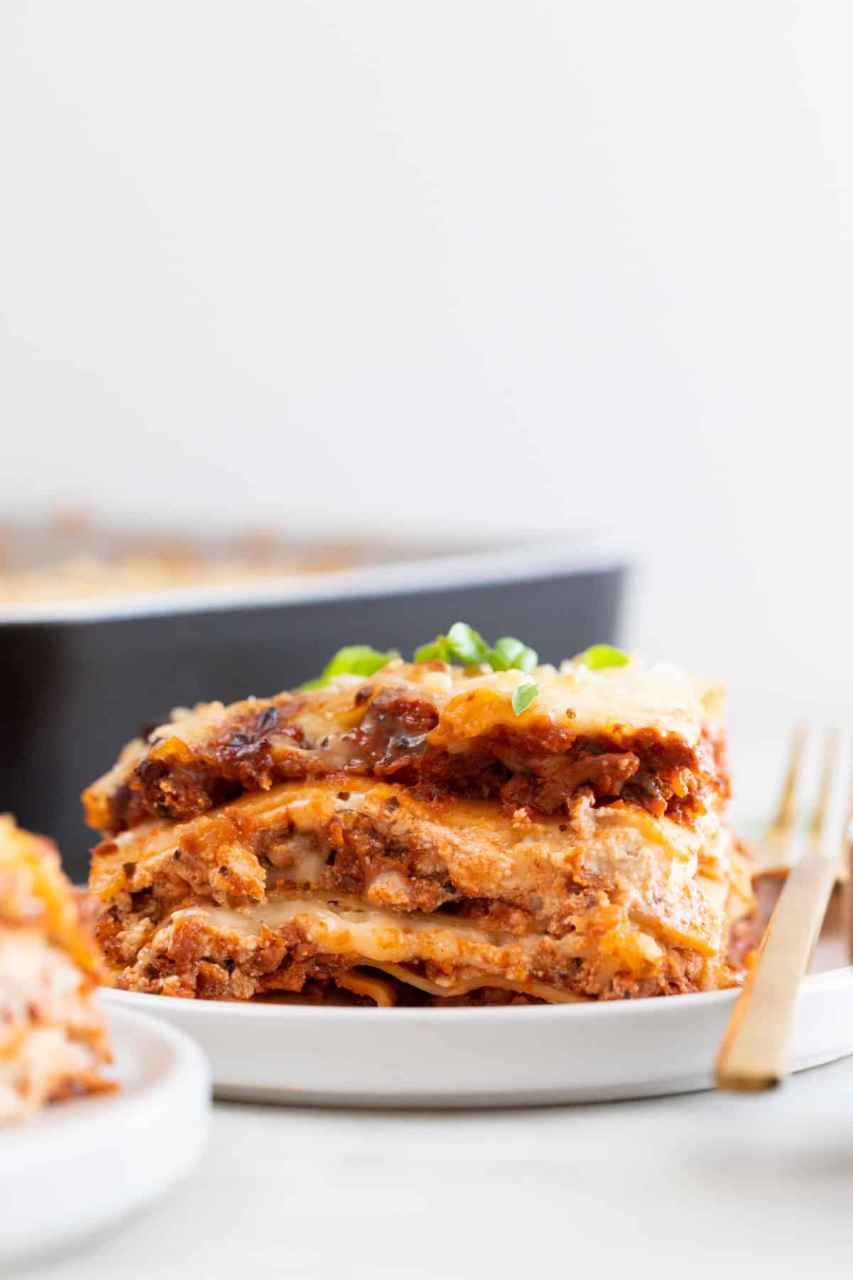 A plate of vegan lasagna with some basil on top.