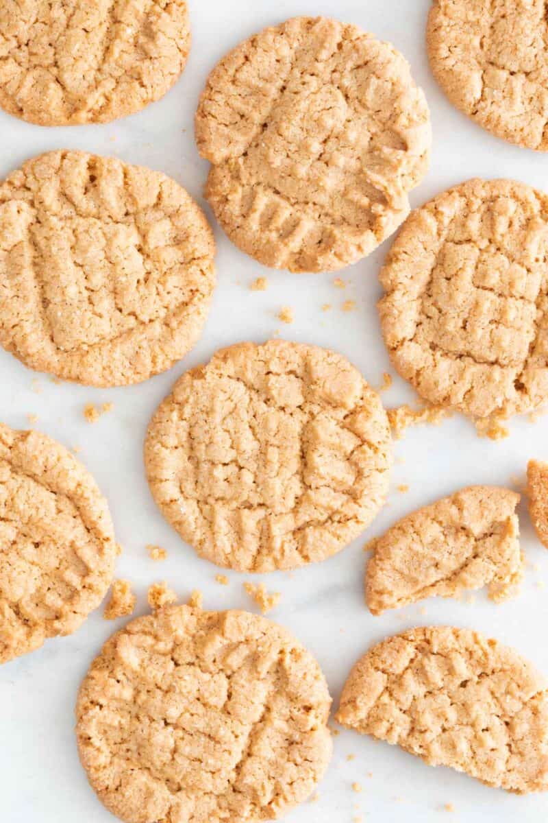 Lots of vegan peanut butter cookies on a marble slab.