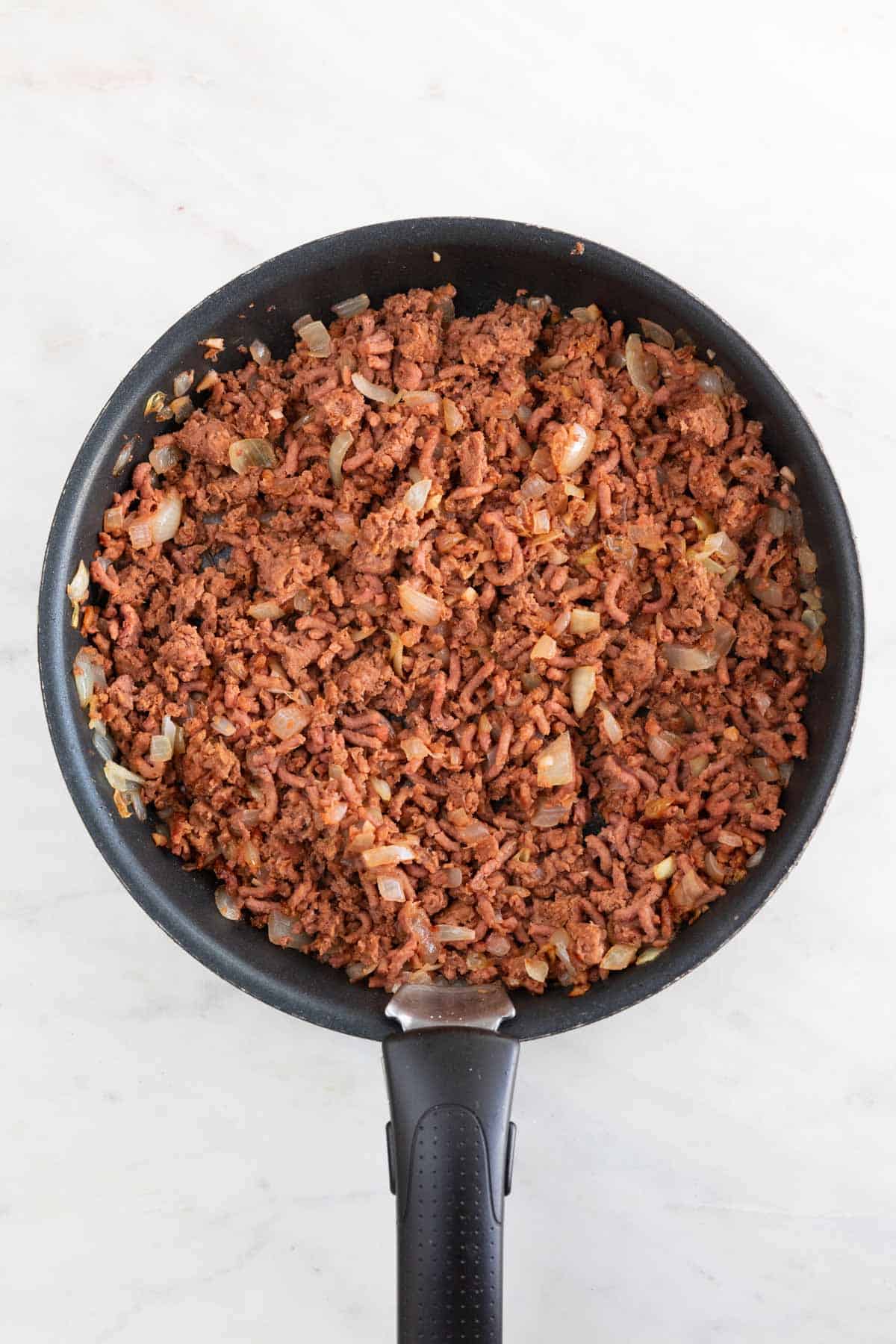 A skillet with cooked onion, garlic, and vegan ground beef.