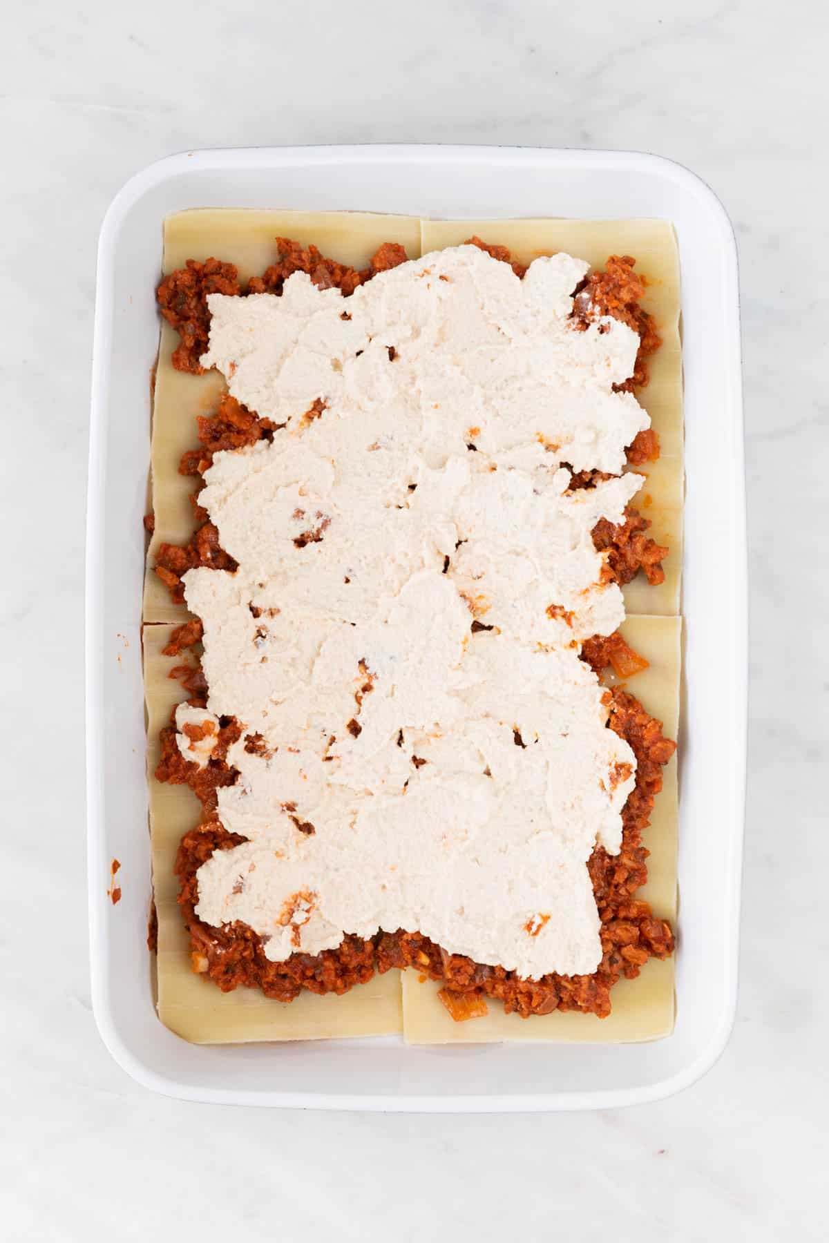 A casserole dish with a layer of vegan ricotta.