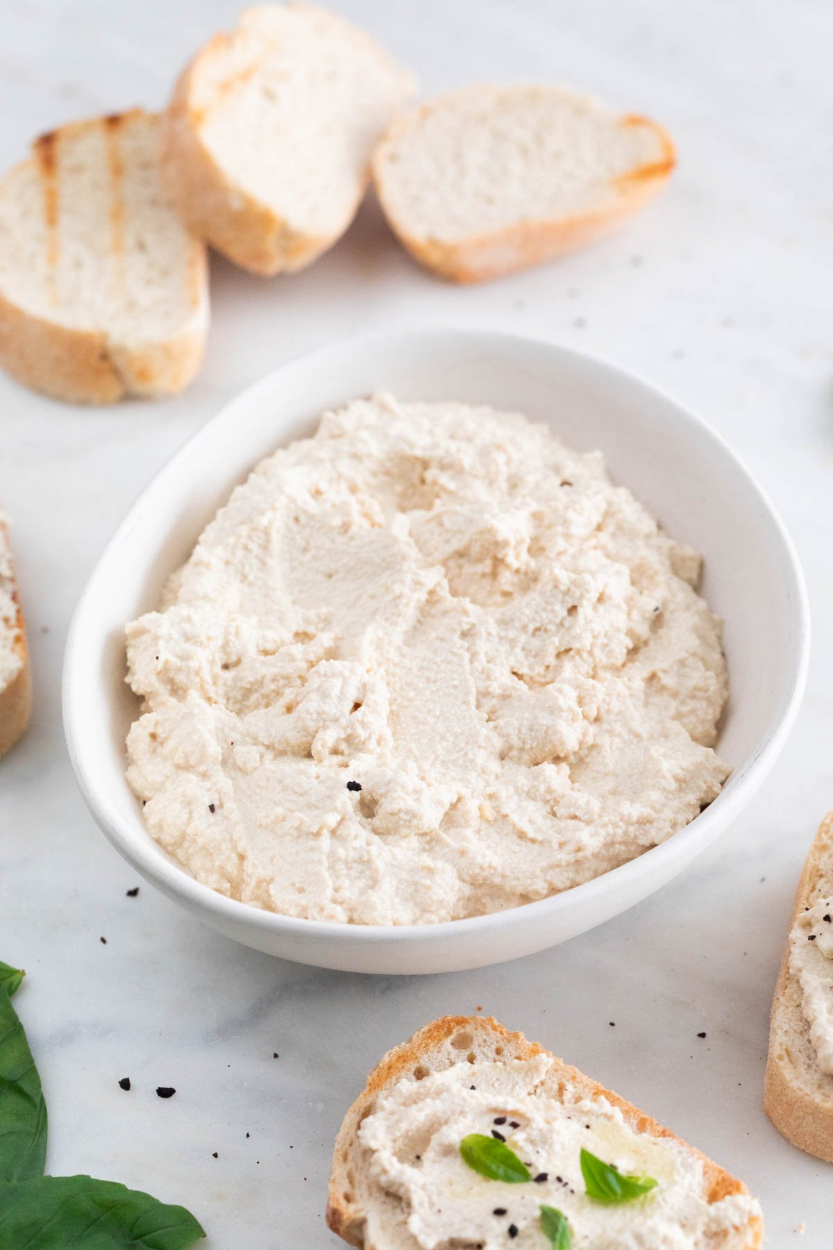 A bowl with vegan tofu ricotta cheese and some bread slices spread with the cheese.