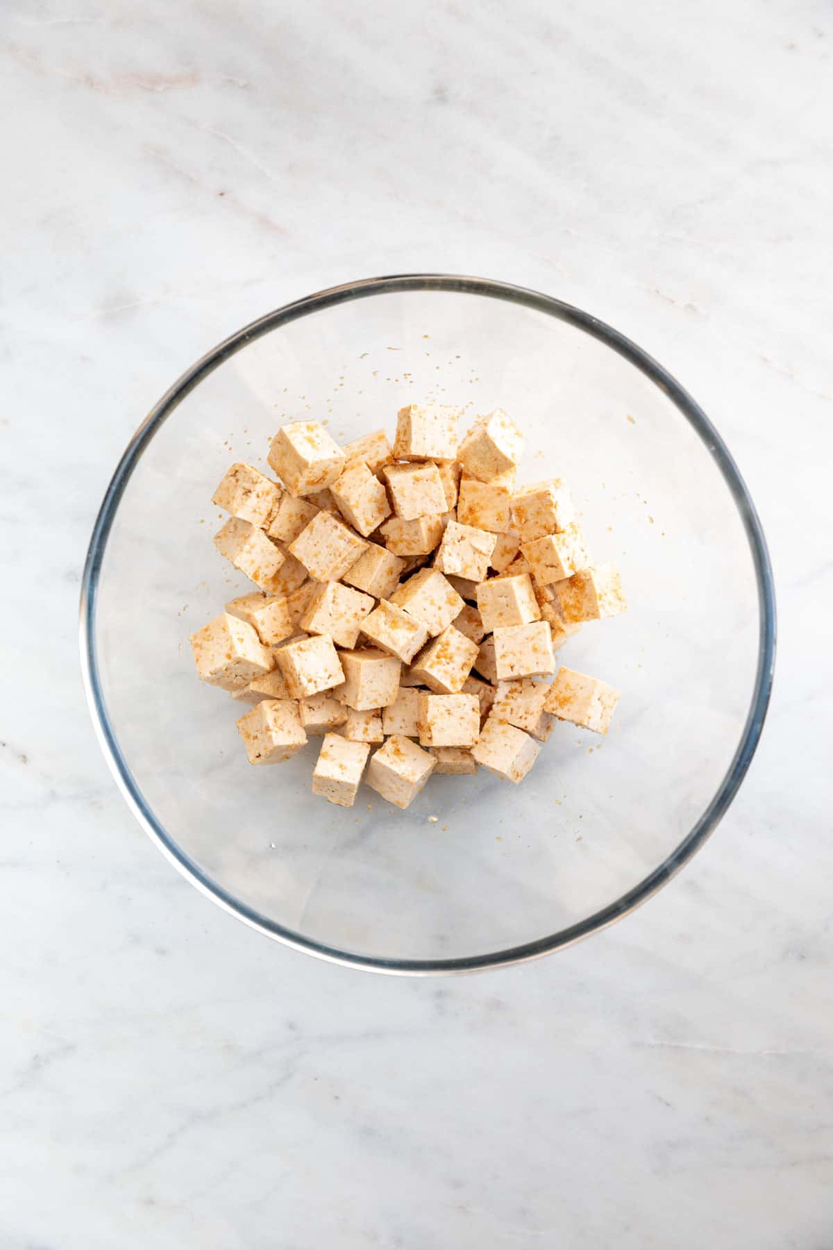 Tofu cubes marinating in a large bowl.