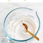 A glass measuring cup with vegan mayonnaise and a spoon.