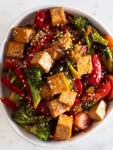 A bowl with tofu stir fry garnished with some sesame seeds.