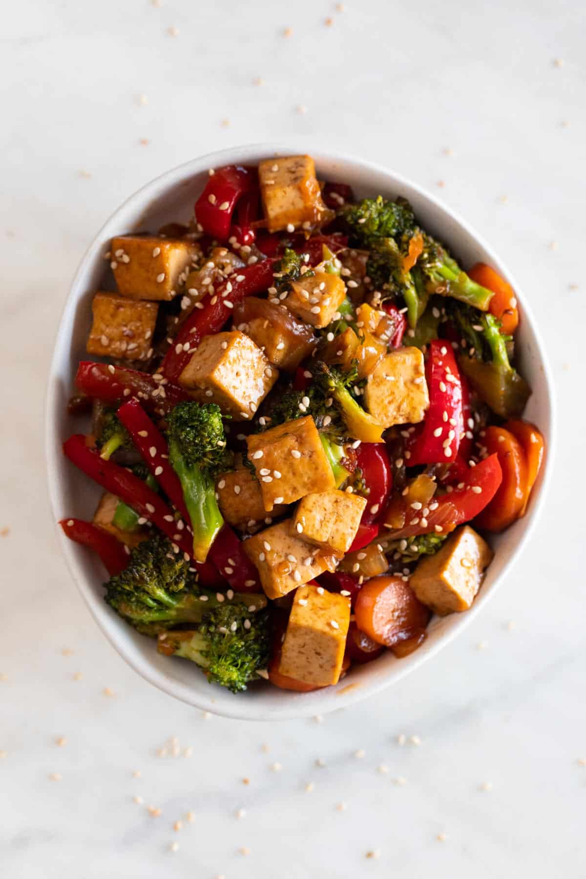 A bowl with tofu stir fry garnished with some sesame seeds.