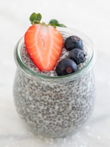 A jar with chia pudding and topped with berries.