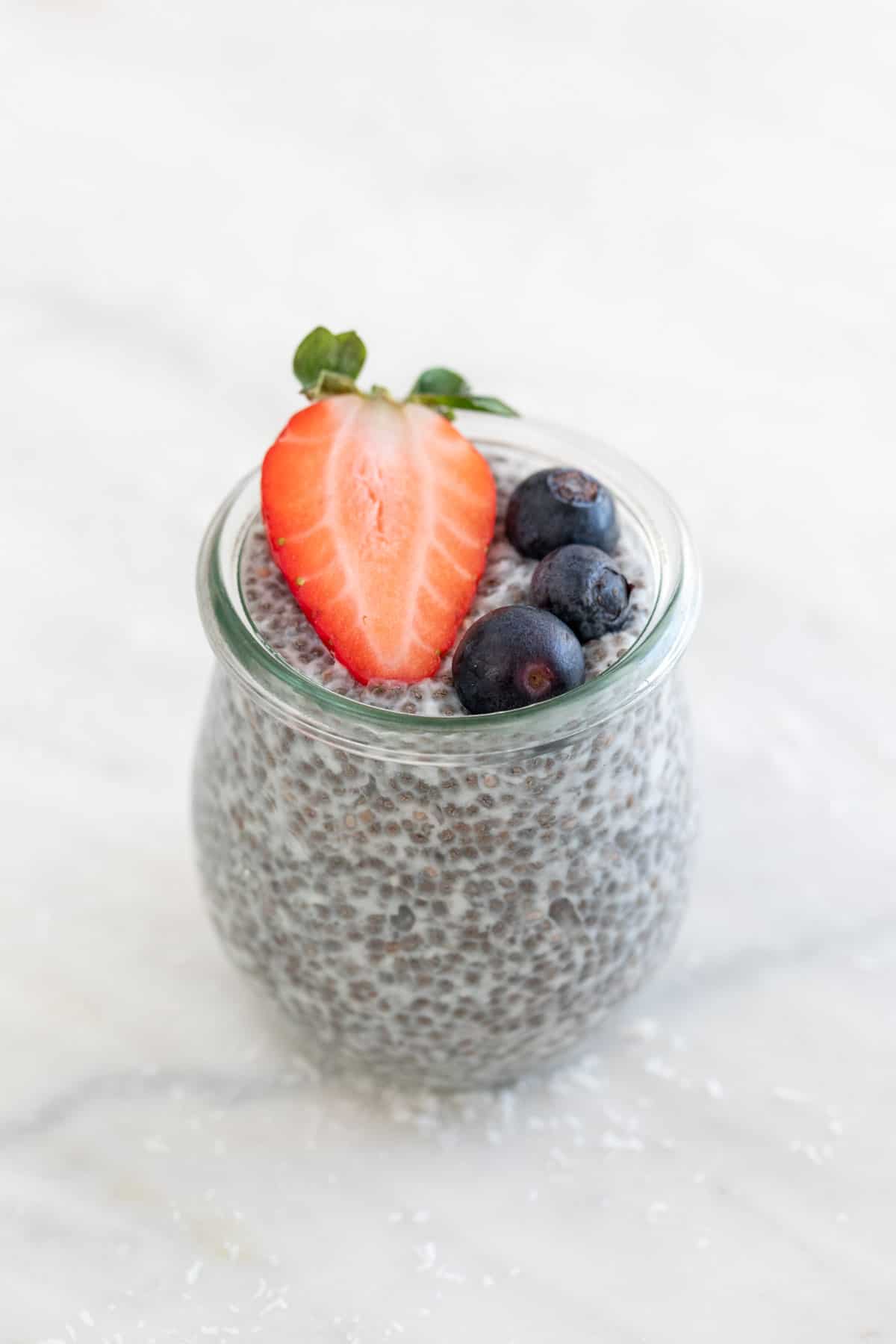 A jar with chia pudding and topped with berries.