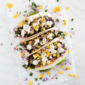 Three vegan tacos onto a white board.