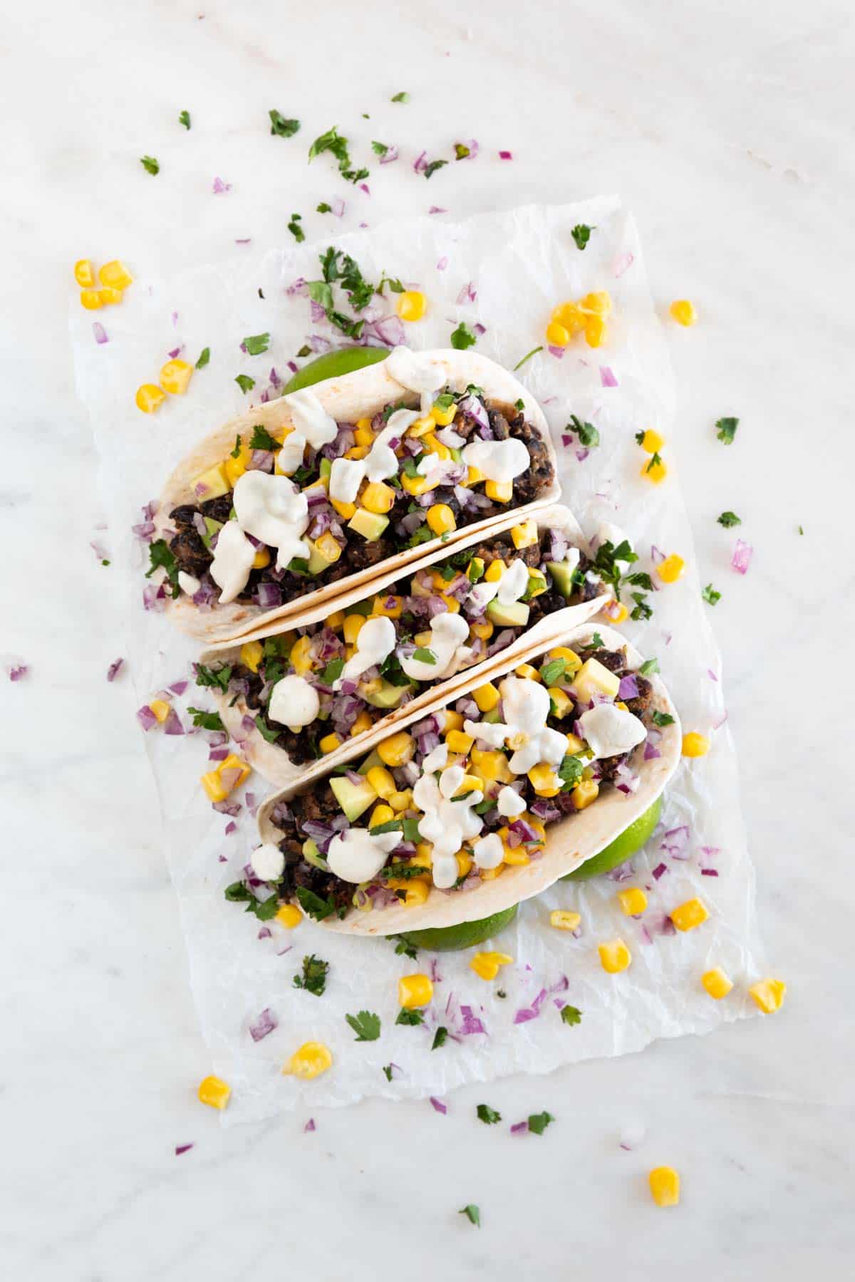 Three vegan tacos onto a white board.