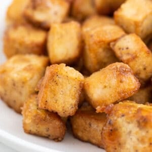 Square photo of a dish with crispy pan-fried tofu cubes.