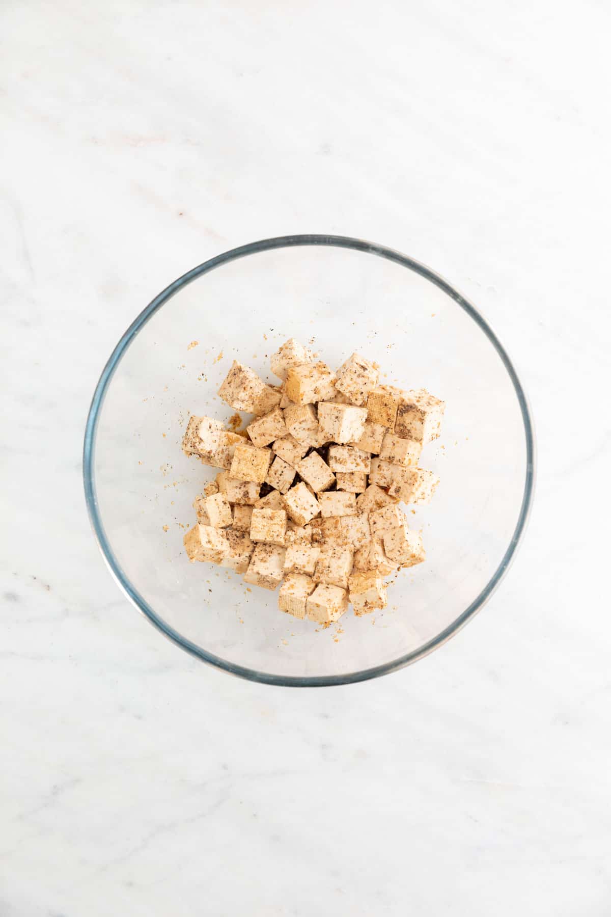 Tofu cubes already mixed with seasonings in a large mixing bowl.