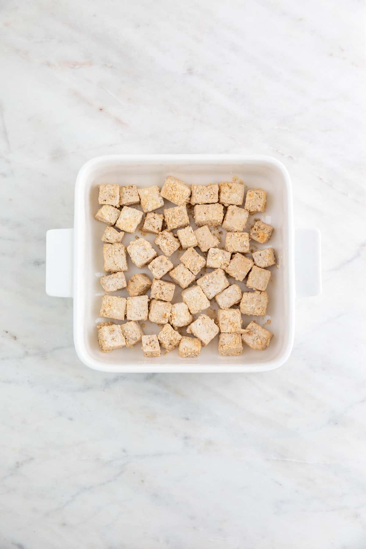 Tofu cubes on a shallow dish already mixed with the cornstarch.