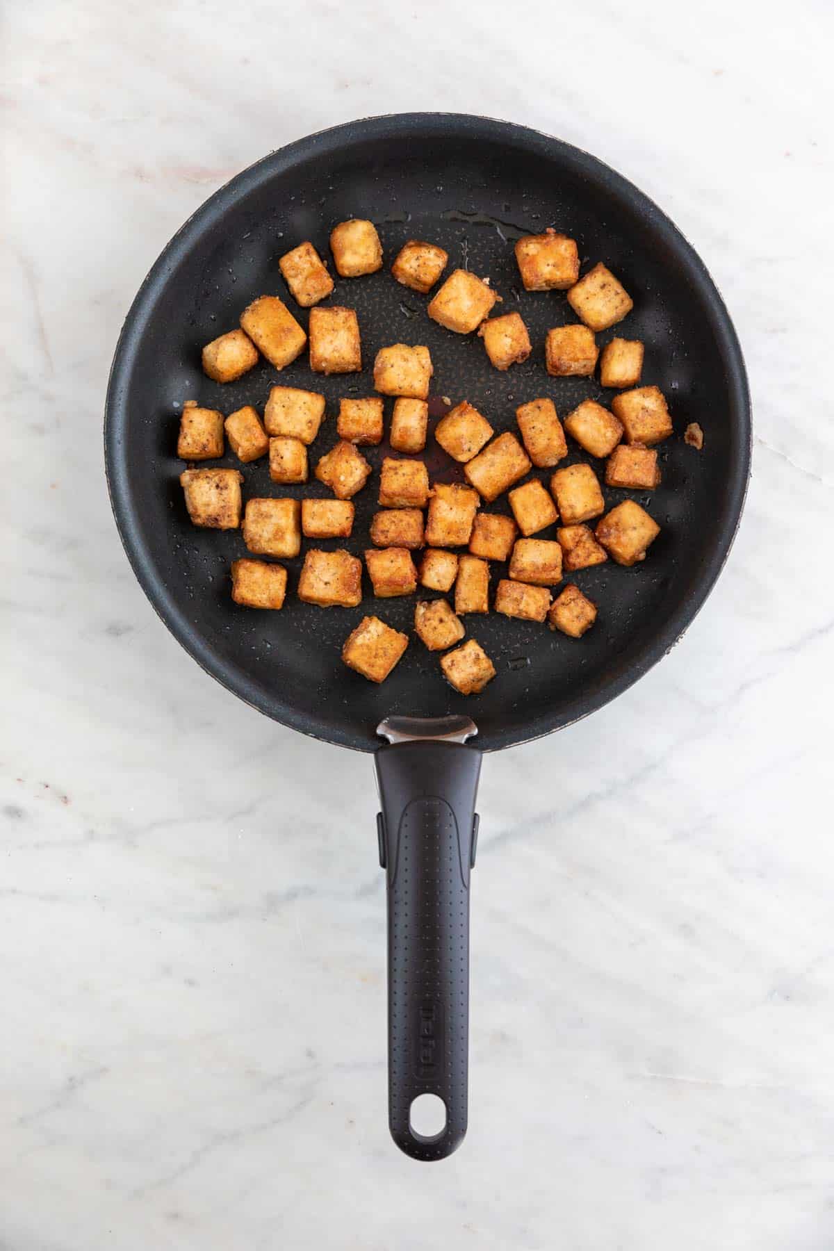 Fried tofu cubes on a non-stick frying pan.