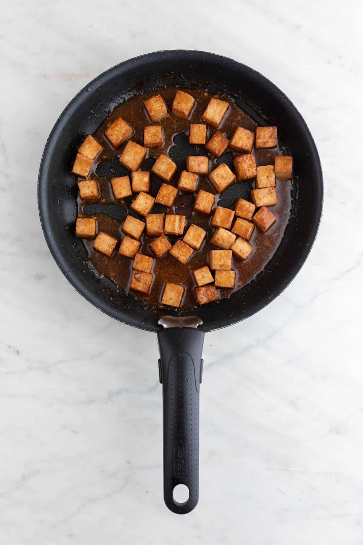 Marinated tofu cubes cooked in a non-stick pan after adding the sauce.