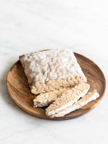 A sliced block of tempeh onto a wooden plate.