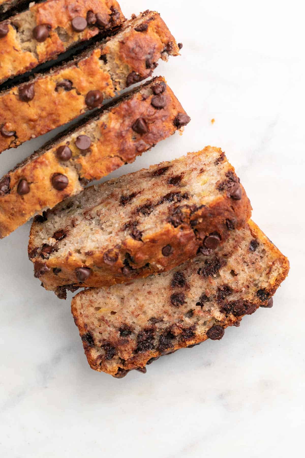 A sliced vegan banana bread on a marble background.