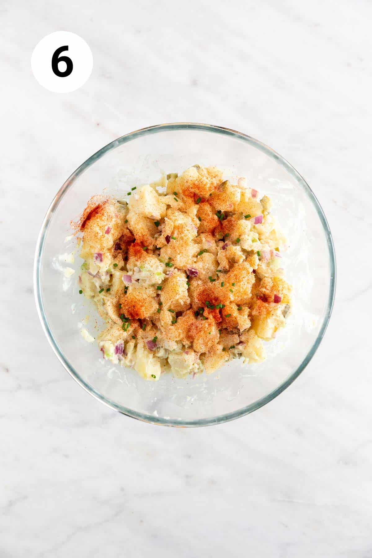 Bowl of vegan potato salad garnished with paprika and chives.