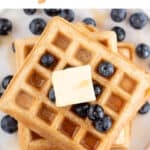 Vegan waffles piled high with blueberries, vegan butter, and maple syrup.