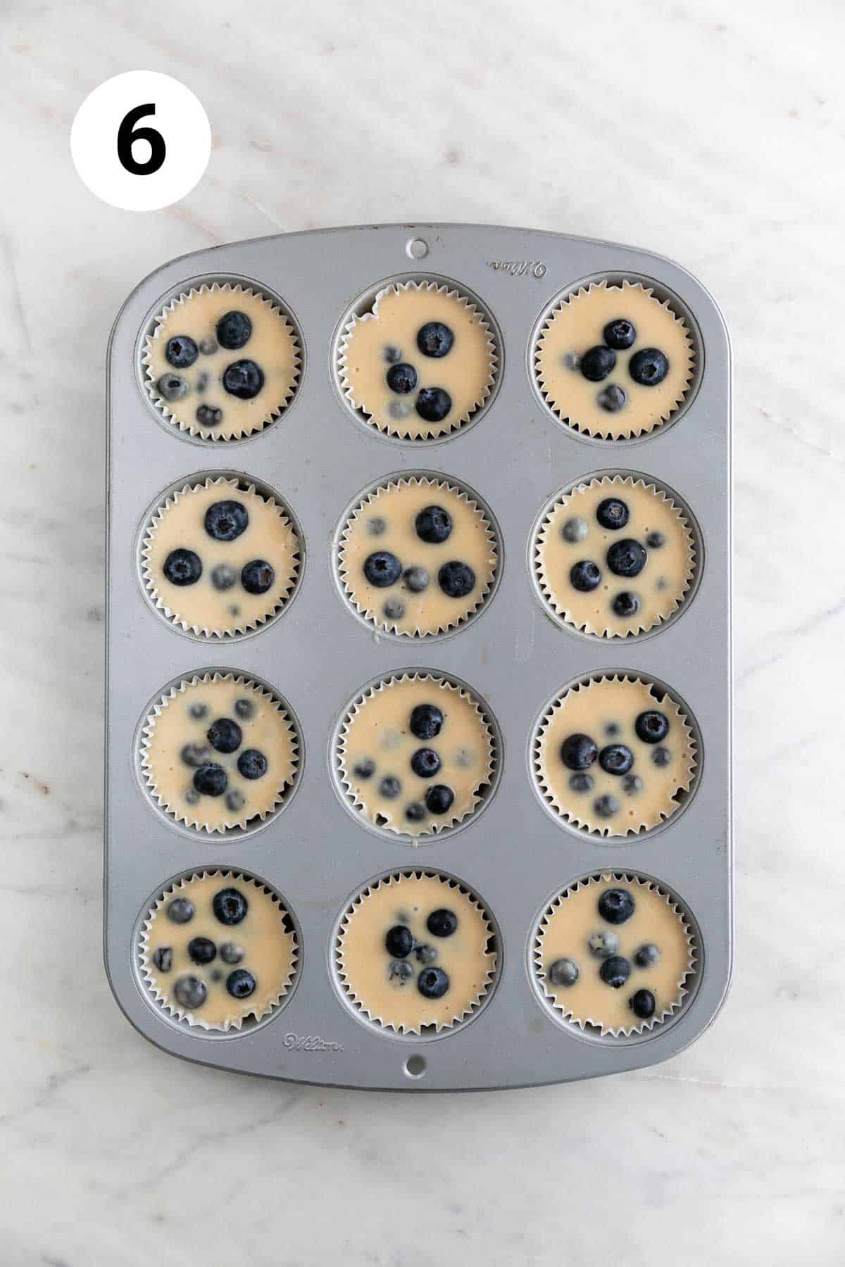 Vegan blueberry muffin batter in a muffin tin.