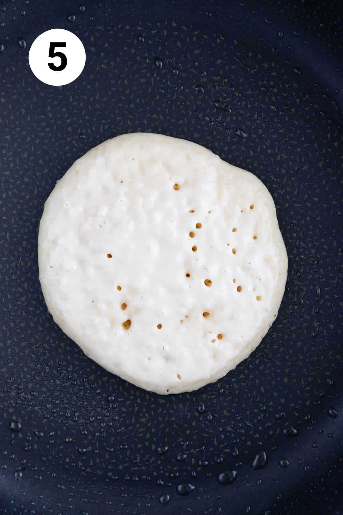 A vegan pancake cooking on a non-stick pan.