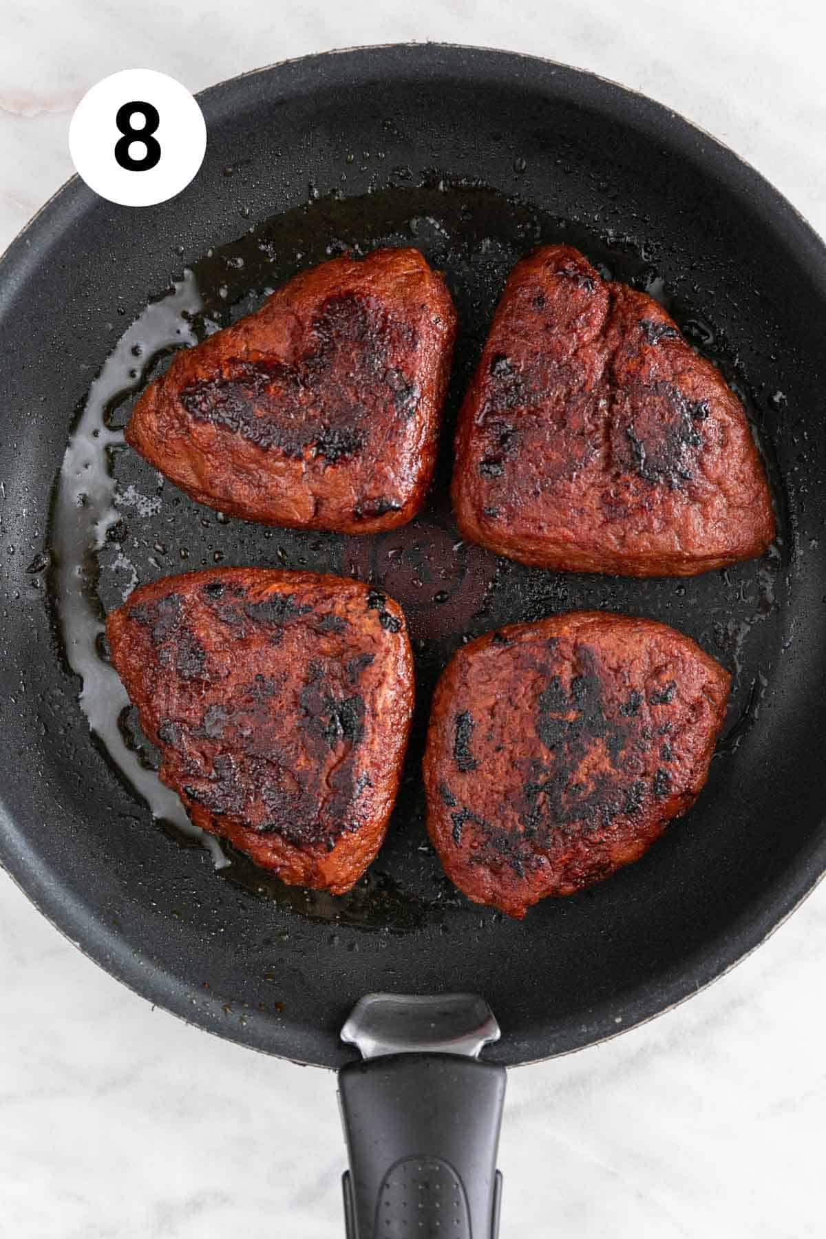 The vegan steaks cooked in a frying pan.