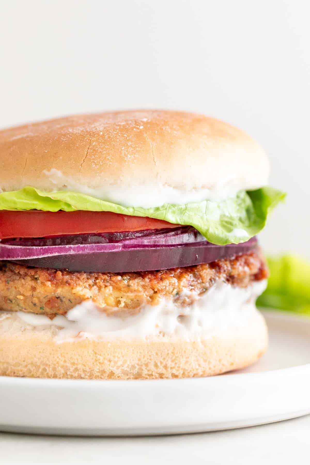 Vegan chickpea patty on bun with lettuce, tomato, red onion, and vegan mayo.