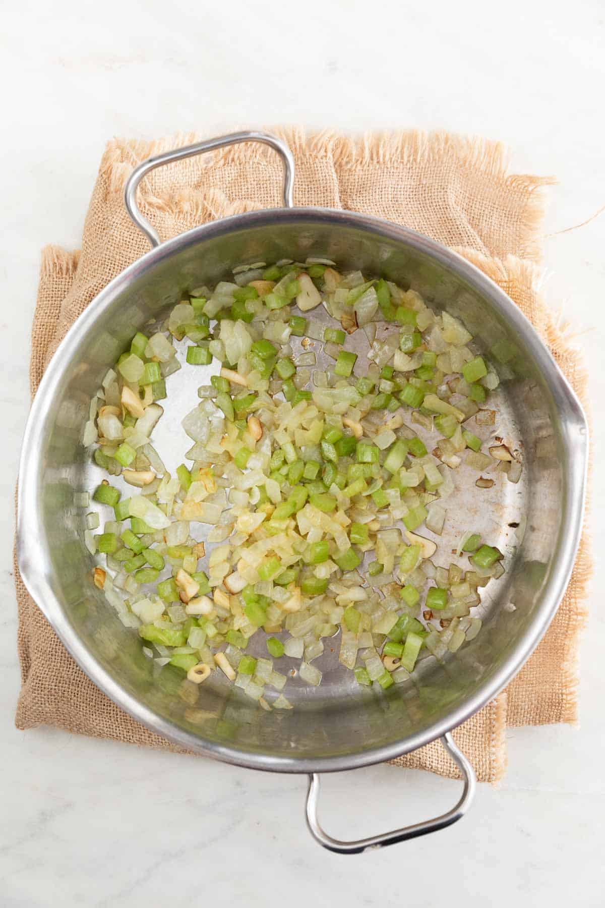 Large pot with sautéed garlic, onion, and celery.