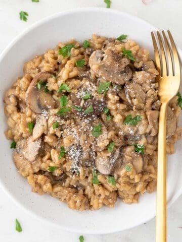 Vegan mushroom risotto plated with a golden fork.
