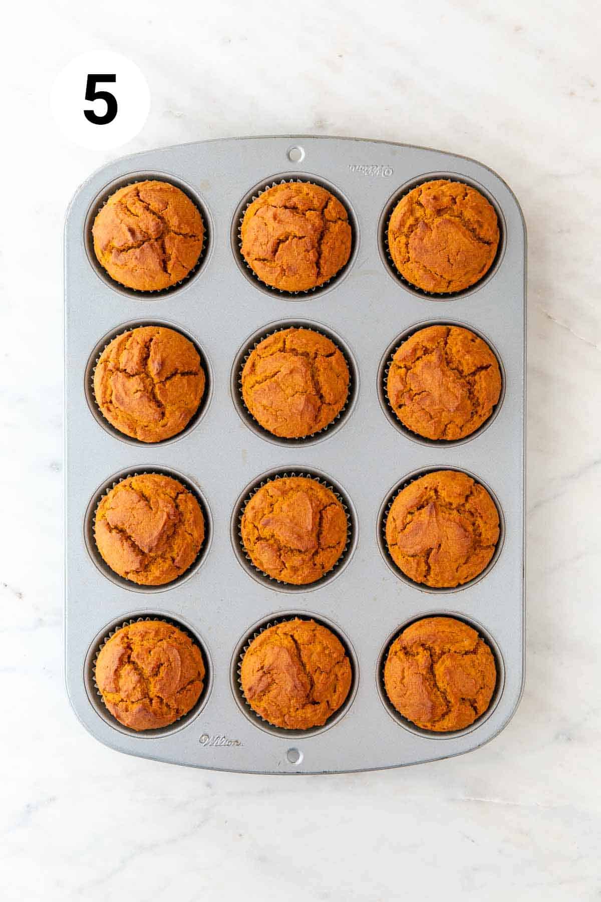 Baked vegan pumpkin muffins in a muffin pan.