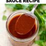A spoon drizzles red enchilada sauce onto a jar filled with red enchilada sauce.