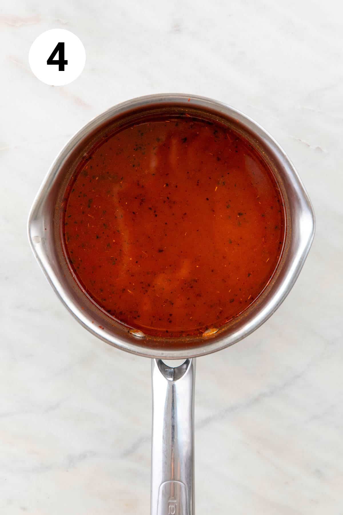 Red enchilada sauce in a saucepan before thickening.