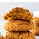 Three vegan pumpkin cookies, one atop another, the upper one frosted and partially nibbled.