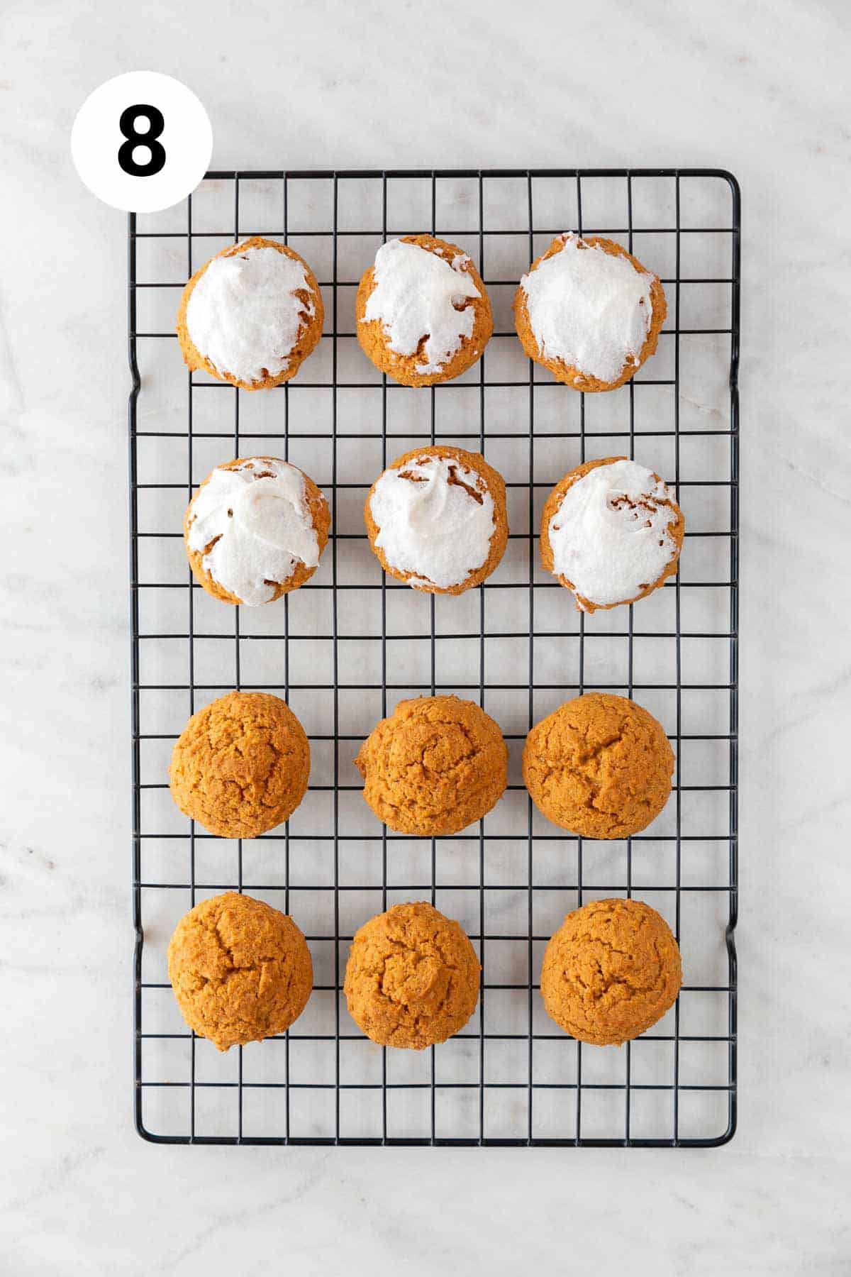 Baked vegan pumpkin cookies onto a cooling rack, some with frosting.