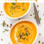 Bowls of vegan pumpkin soup adorned with coconut milk, parsley, and black pepper.