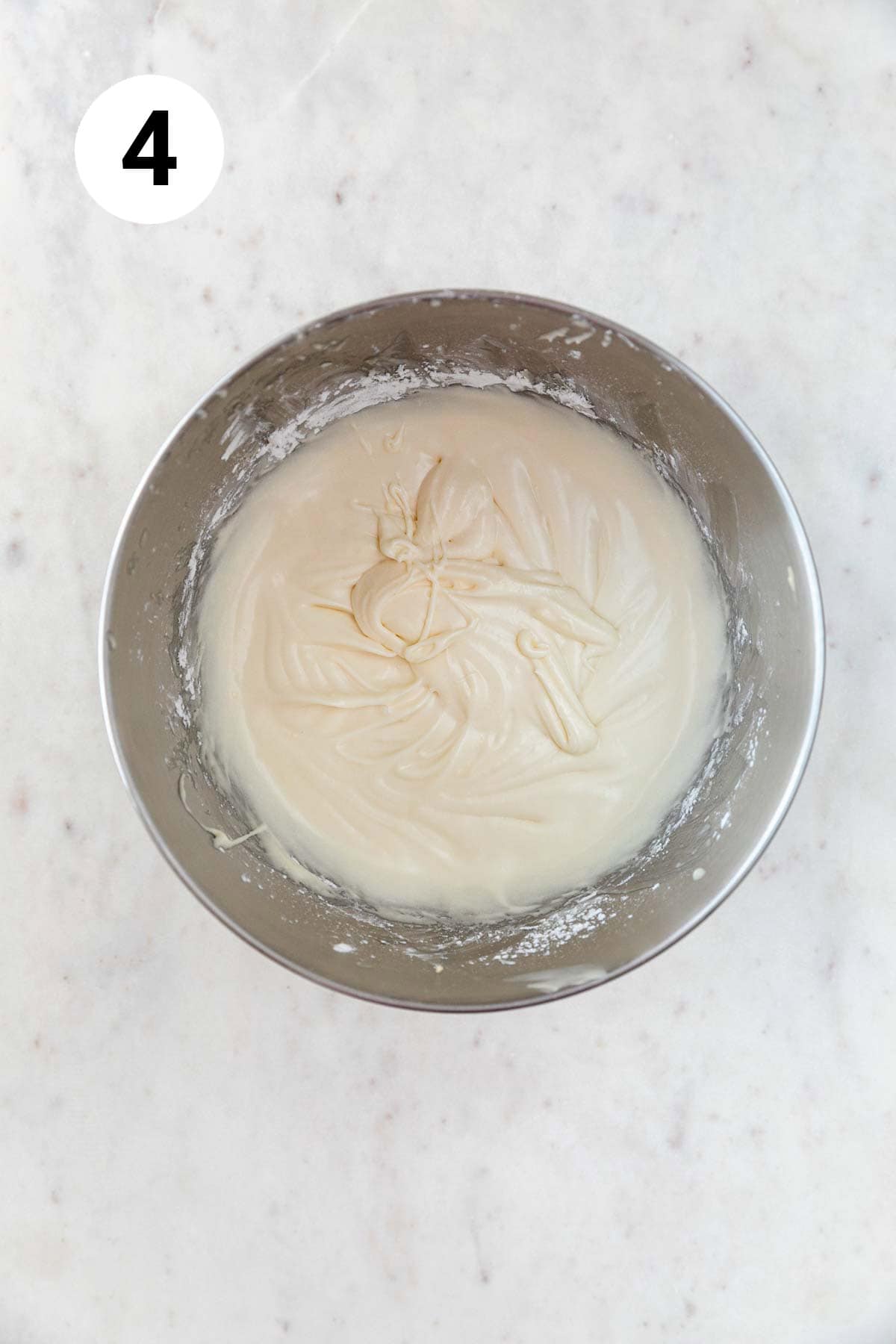 Vegan cream cheese frosting in the bowl of an electric mixer.
