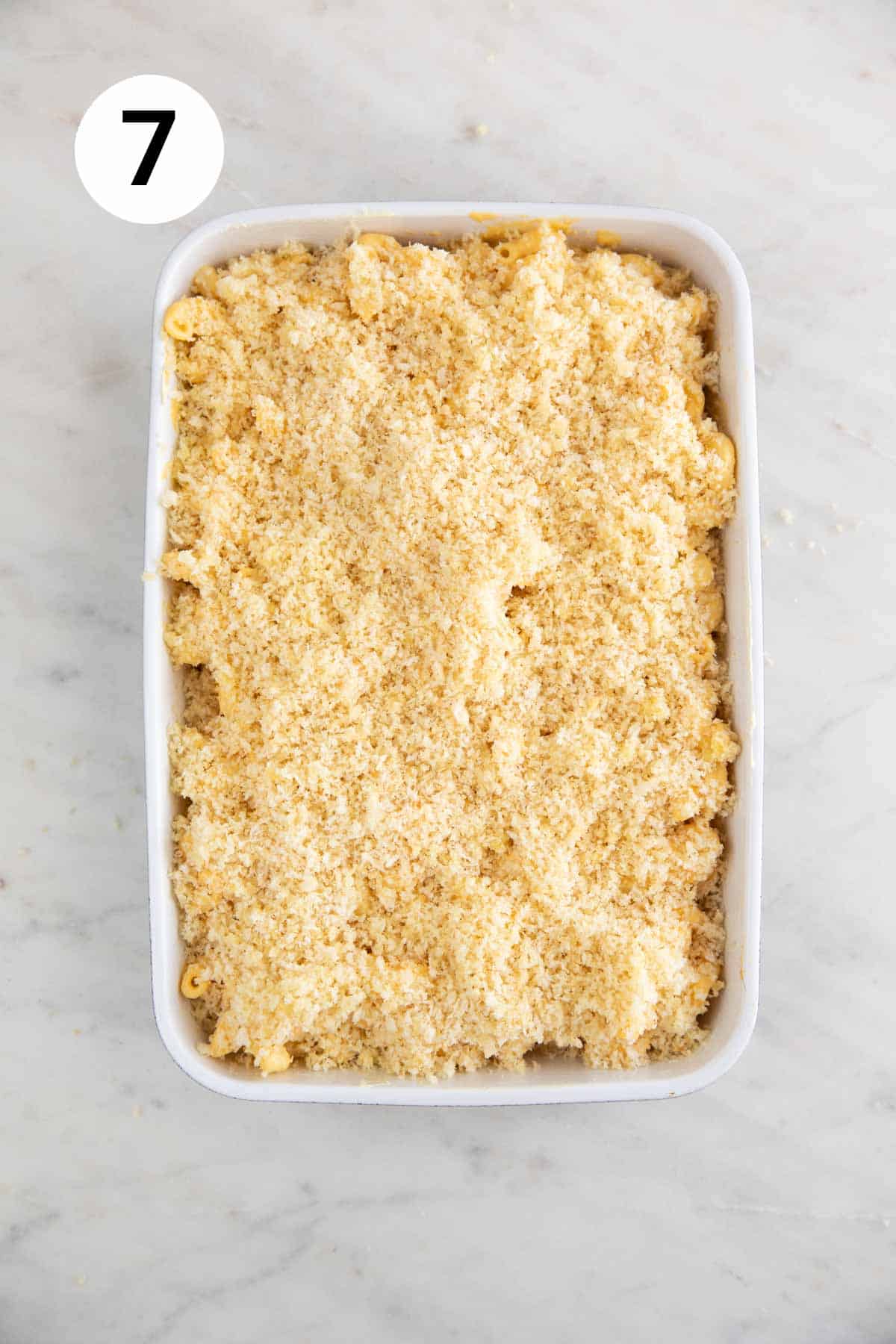 Baking dish with vegan mac and cheese topped with breadcrumbs before baking.