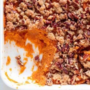 A scoop taken out of vegan sweet potato casserole from a baking dish.