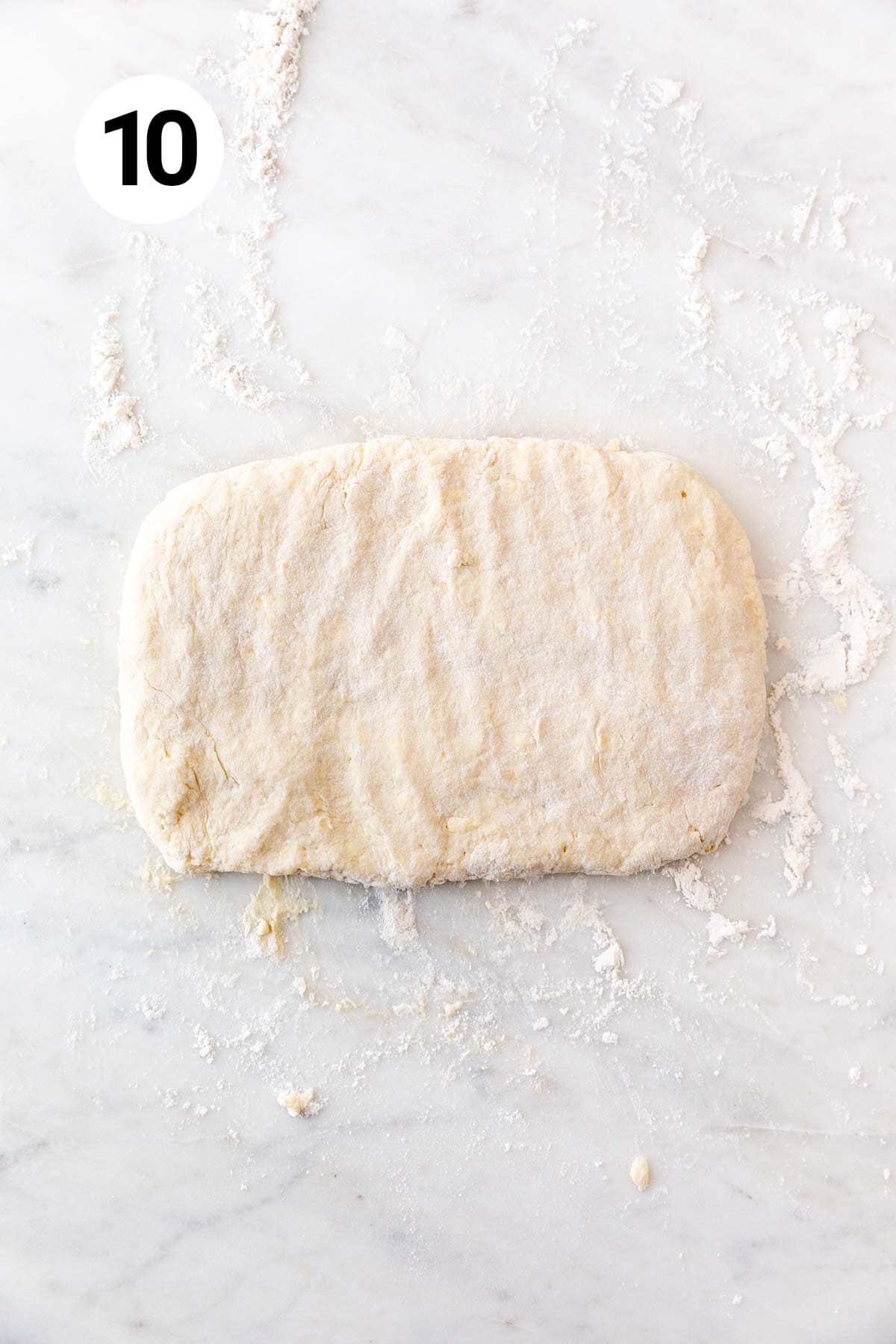 A rectangle of dough on a floured marble surface.