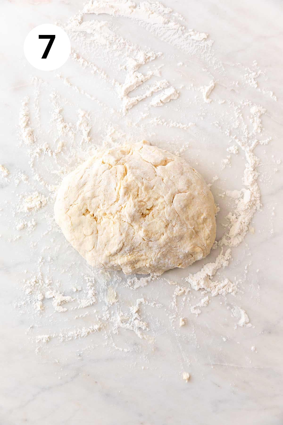 Vegan biscuits dough on a floured marble surface.
