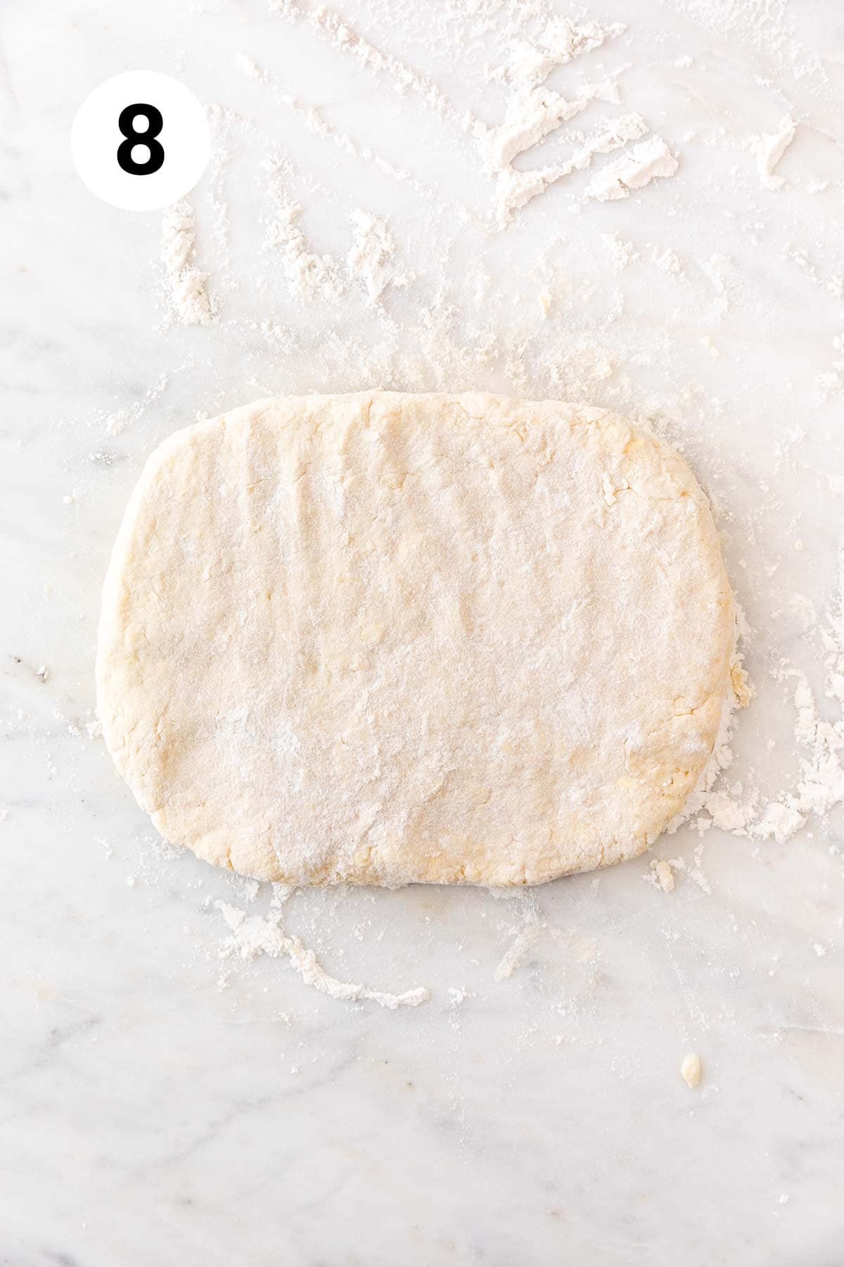 A rectangle of dough on a floured marble surface.