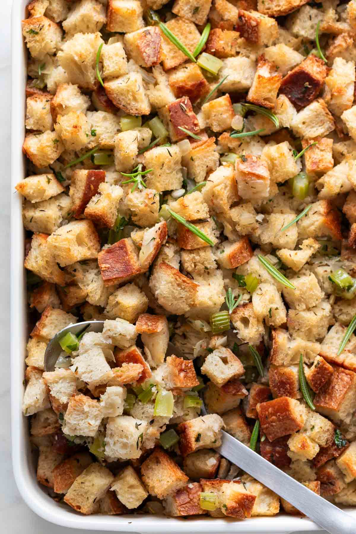 Vegan stuffing in a baking dish with a serving spoon.